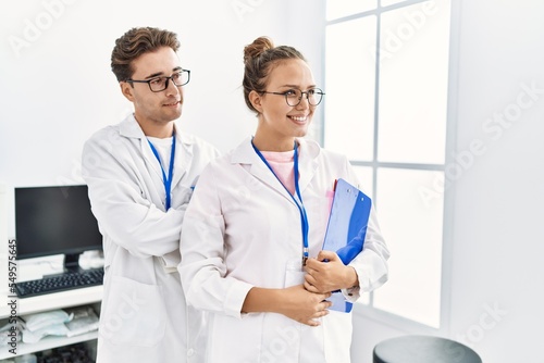 Man and woman wearing scientist uniform holding clipboard working at laboratory