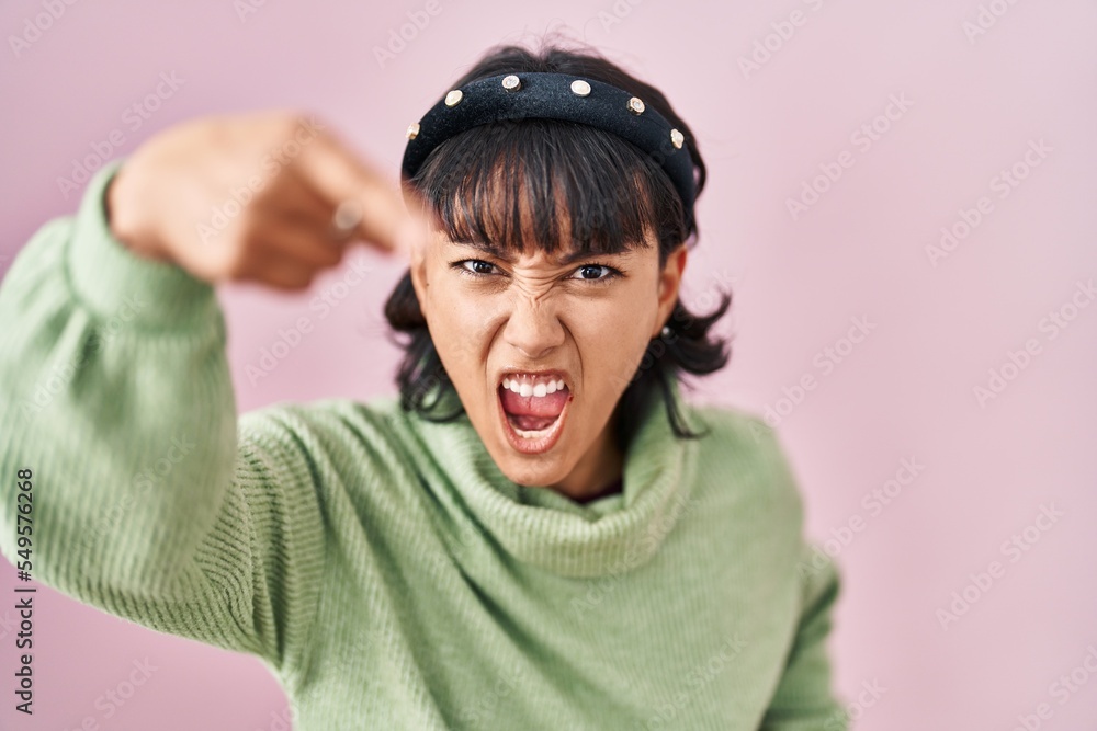 Young beautiful woman standing over pink background pointing displeased and frustrated to the camera, angry and furious with you Young beautiful woman standing over pink background pointing displeased and frustrated to the camera, angry and furious with you