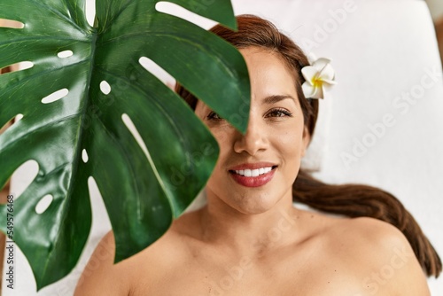 Young latin woman smiling confident relaxed lying on massage table