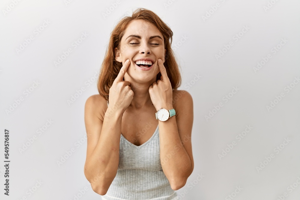 Beautiful caucasian woman standing over isolated background smiling with open mouth, fingers pointing and forcing cheerful smile Beautiful caucasian woman standing over isolated background smiling with open mouth, fingers pointing and forcing cheerful smile