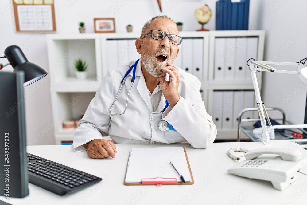 Mature doctor man at the clinic touching mouth with hand with painful expression because of toothache or dental illness on teeth. dentist Mature doctor man at the clinic touching mouth with hand with painful expression because of toothache or dental illness on teeth. dentist