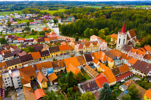 Aerial view of historical centre of Blatna in autumn day overlooking gothic church bell tower and ancient Water castle, South Bohemian Region, Czech Republic..