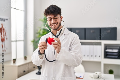 Young hispanic man wearing doctor uniform auscultating heart at clinic © Krakenimages.com