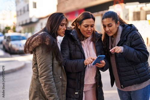 Three woman mother and daughters using smartphone at street