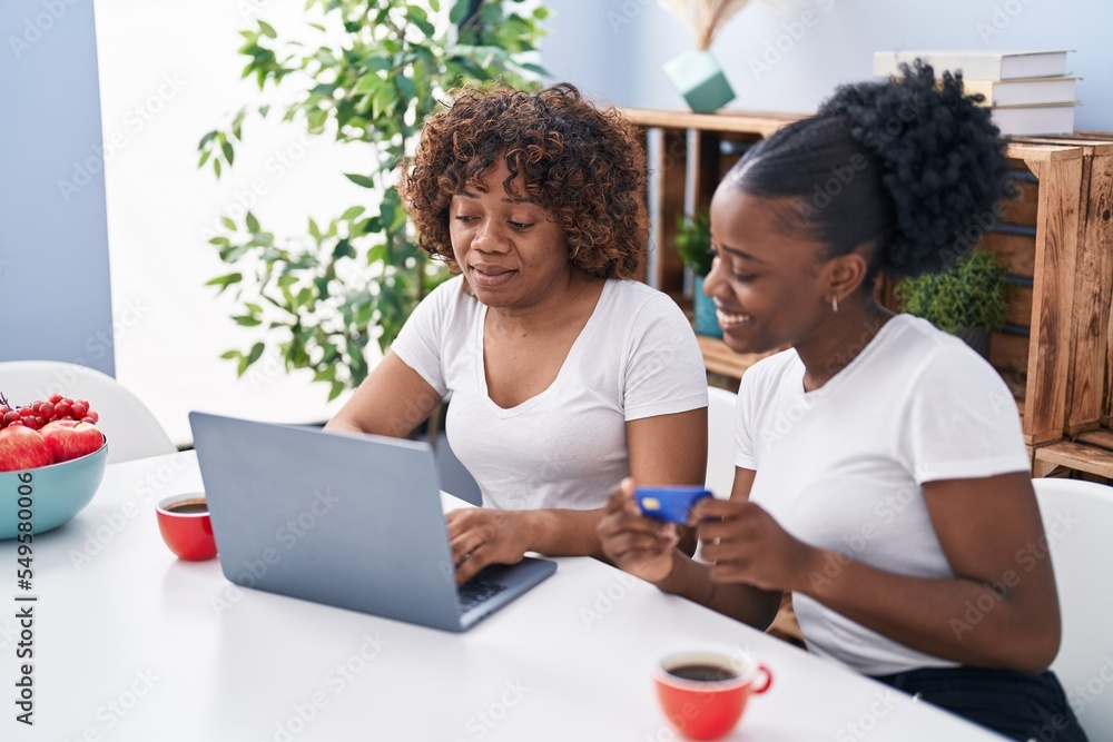 African american women mother and daughter using laptop and credit card at home