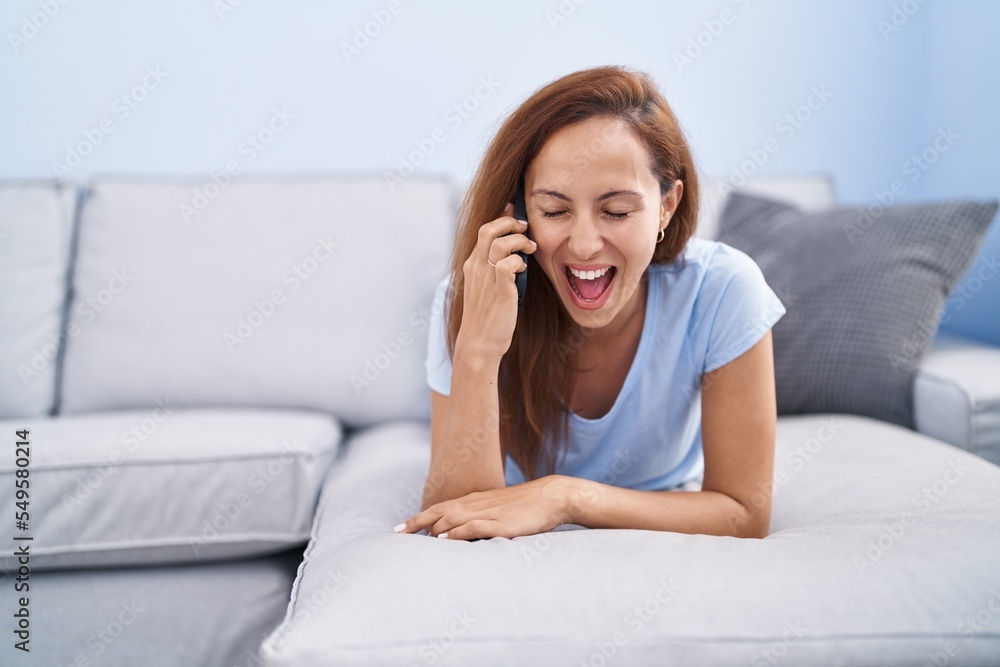 Young woman talking on the smartphone lying on sofa at home Young woman talking on the smartphone lying on sofa at home