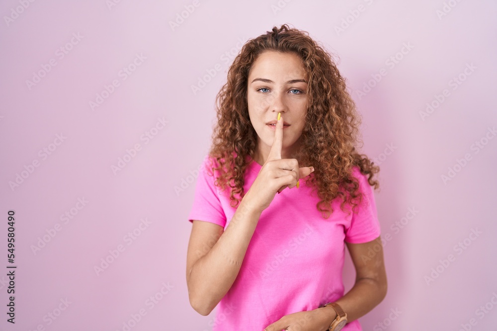 Young caucasian woman standing over pink background asking to be quiet with finger on lips. silence and secret concept. Young caucasian woman standing over pink background asking to be quiet with finger on lips. silence and secret concept.