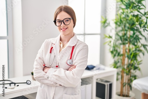 Young blonde woman wearing doctor uniform standing with arms crossed gesture at clinic © Krakenimages.com