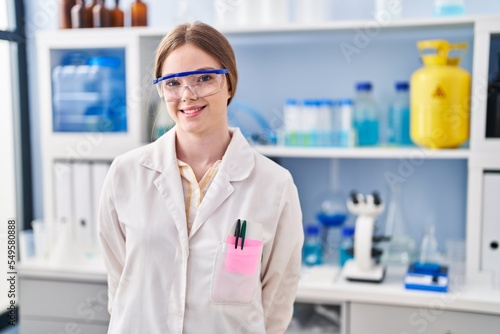 Young blonde woman wearing scientist uniform standing at laboratory
