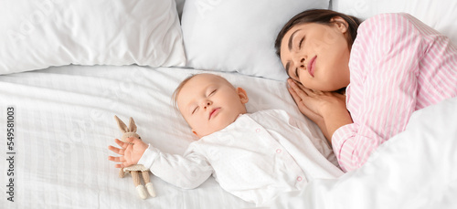 Young woman and her cute baby sleeping in bed