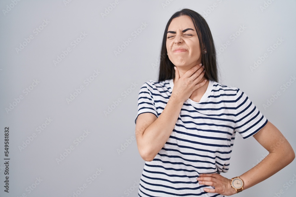Young brunette woman wearing striped t shirt touching painful neck, sore throat for flu, clod and infection Young brunette woman wearing striped t shirt touching painful neck, sore throat for flu, clod and infection