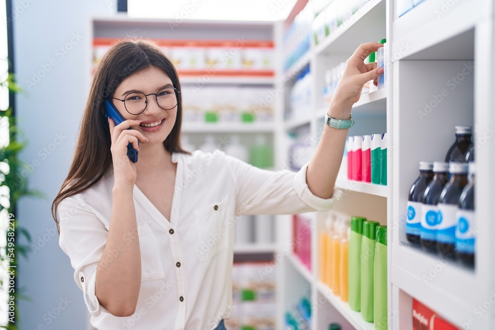 Young caucasian woman customer smiling confident talking on smartphone at pharmacy