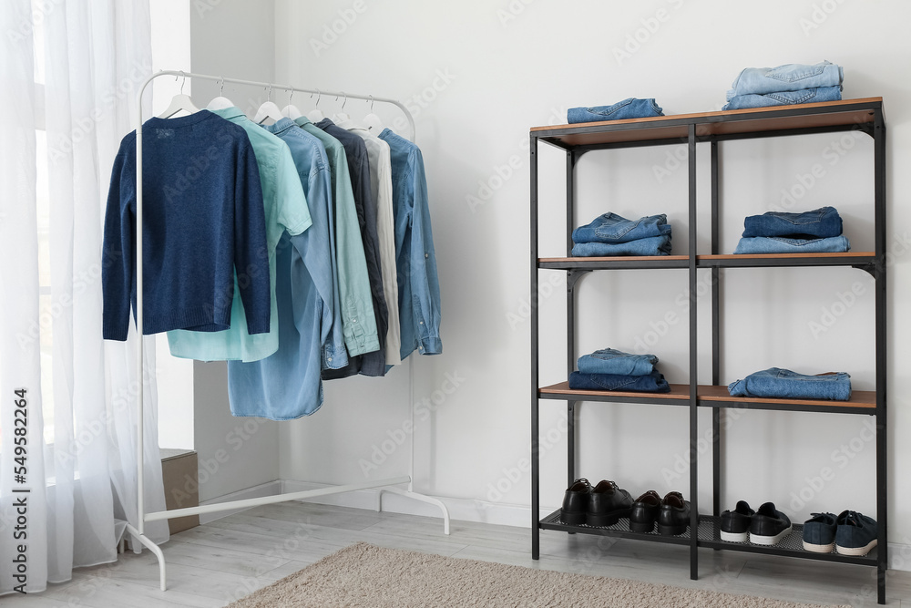 Shelving unit and rack with male clothes near light wall