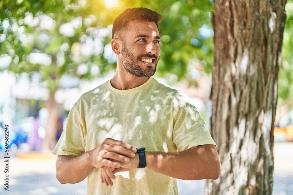Young hispanic man smiling confident looking watch at park Young hispanic man smiling confident looking watch at park