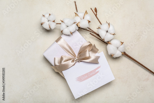 Gift box with card and cotton branch on light background