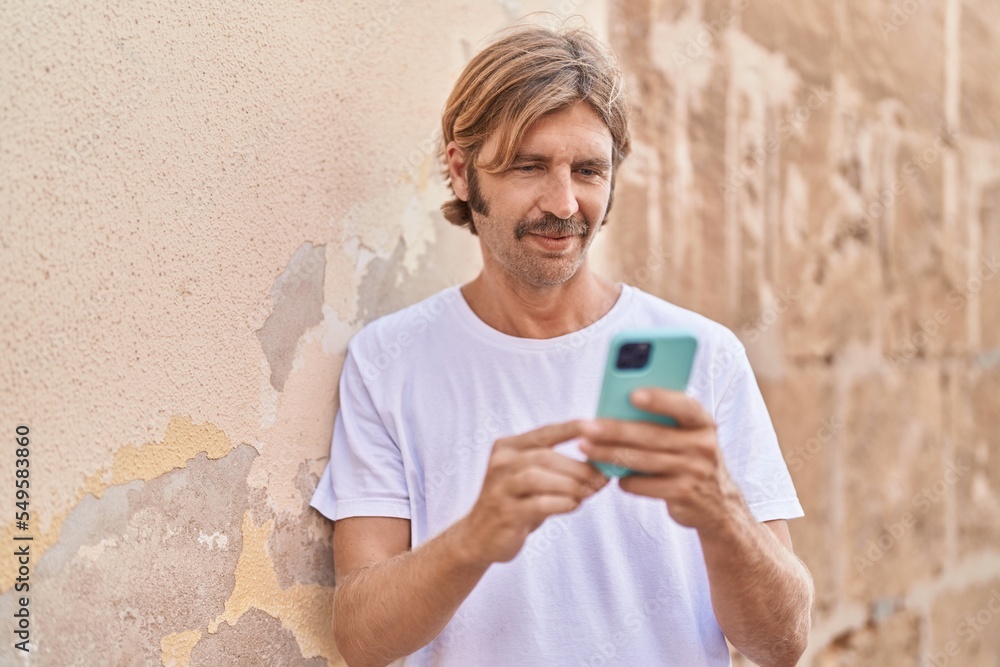 Fototapeta premium Young blond man using smartphone at street