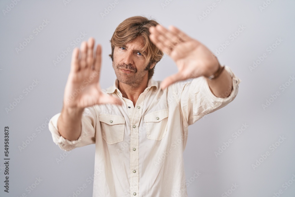Middle age man standing over isolated background doing frame using hands palms and fingers, camera perspective Middle age man standing over isolated background doing frame using hands palms and fingers, camera perspective