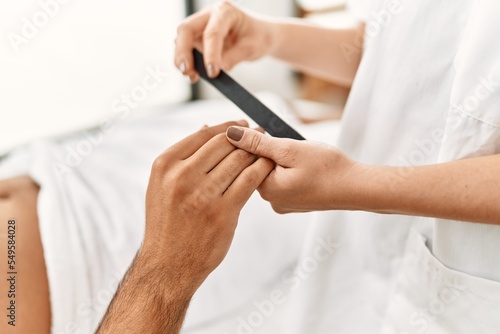 Young hispanic man relaxed having manicure session at beauty center