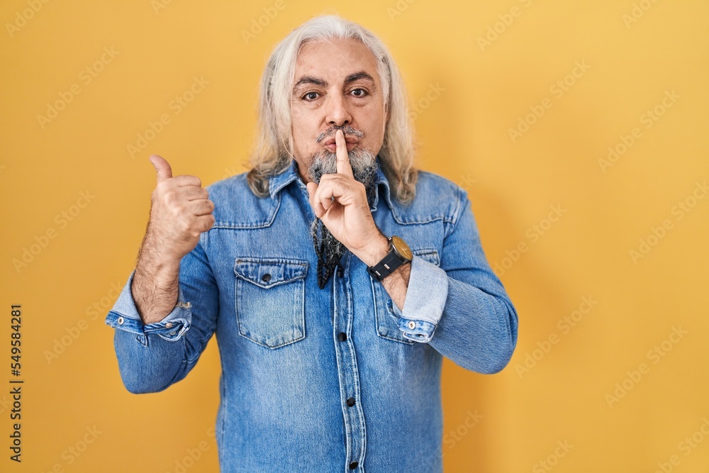 Middle age man with grey hair standing over yellow background asking to be quiet with finger on lips pointing with hand to the side. silence and secret concept. Middle age man with grey hair standing over yellow background asking to be quiet with finger on lips pointing with hand to the side. silence and secret concept.