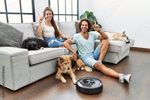 Young hispanic couple relaxing at home by vacuum robot surprised with an idea or question pointing finger with happy face, number one © Krakenimages.com