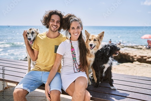 Photography Man and woman couple smiling confident hugging each other with dogs at seaside