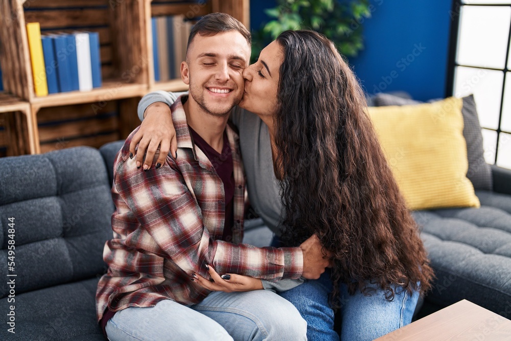 Man and woman couple hugging each other sitting on sofa at home Man and woman couple hugging each other sitting on sofa at home