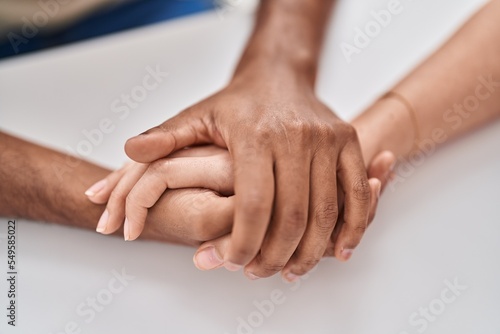 Man and woman couple sitting on table with hands together at home