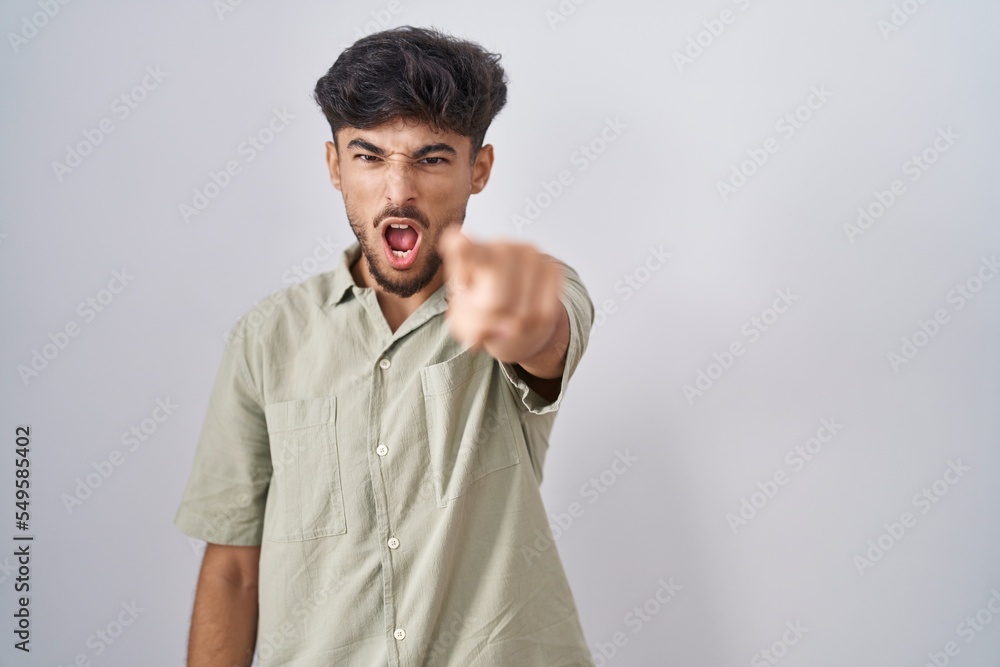 Arab man with beard standing over white background pointing displeased and frustrated to the camera, angry and furious with you Arab man with beard standing over white background pointing displeased and frustrated to the camera, angry and furious with you