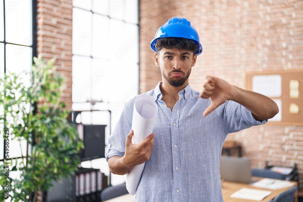 Arab man with beard wearing architect hardhat at construction office with angry face, negative sign showing dislike with thumbs down, rejection concept Arab man with beard wearing architect hardhat at construction office with angry face, negative sign showing dislike with thumbs down, rejection concept