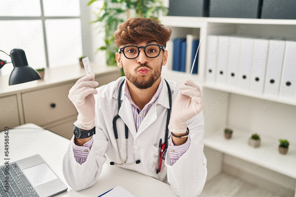 Arab doctor man with beard holding covid test looking at the camera blowing a kiss being lovely and sexy. love expression. Arab doctor man with beard holding covid test looking at the camera blowing a kiss being lovely and sexy. love expression.