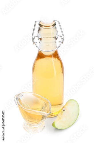 Bottle and gravy boat of apple cider vinegar on white background