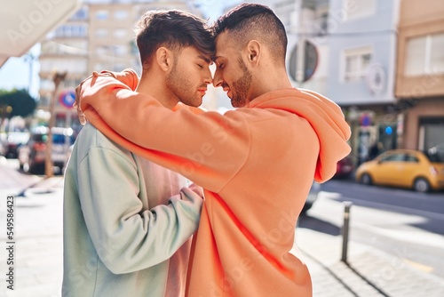 Two man couple hugging each other standing at street