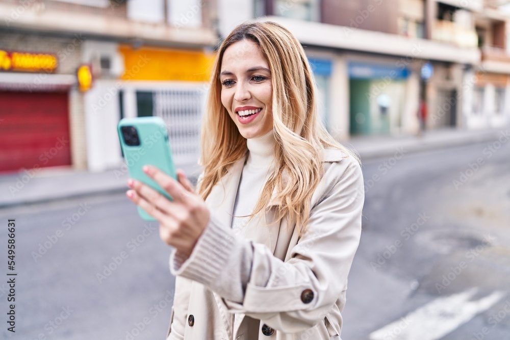 Fototapeta premium Young blonde woman smiling confident having video call at street