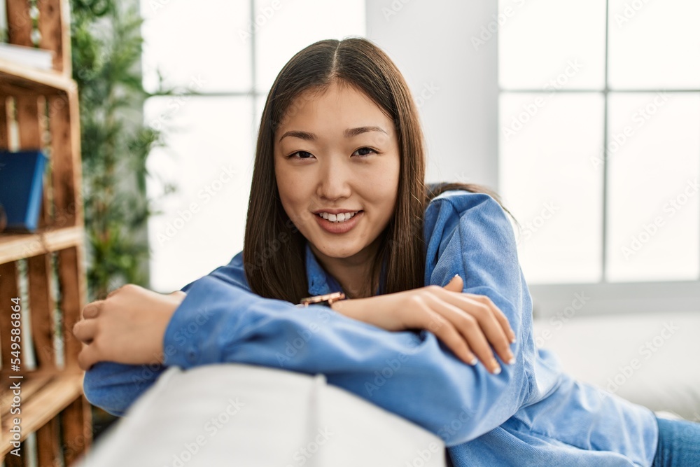Young chinese girl smiling happy sitting on the sofa at home. Stock ...