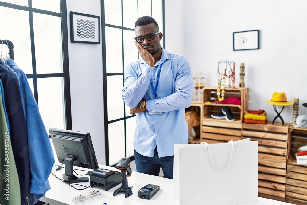 Young african man working as manager at retail boutique thinking looking tired and bored with depression problems with crossed arms.