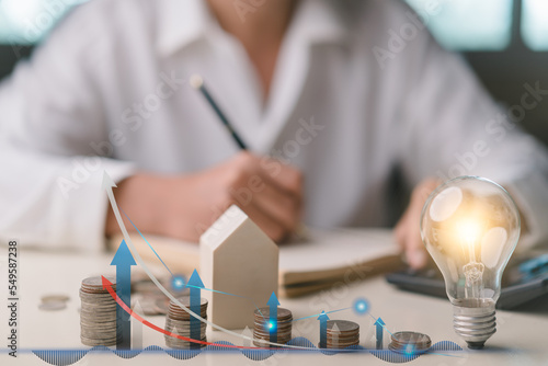 Businessman taking notes and using calculator to calculate, Stacking coins, graph up icon, wooden house, light bulb. Plan revenue and expenses, target success growth, finance profit planning 2023.