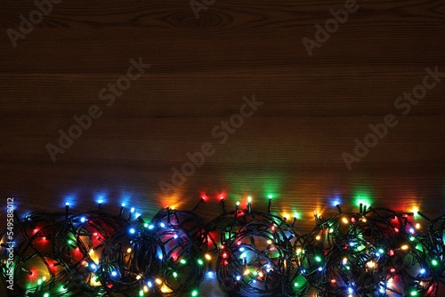Colorful Christmas lights on wooden table  top view. Space for text