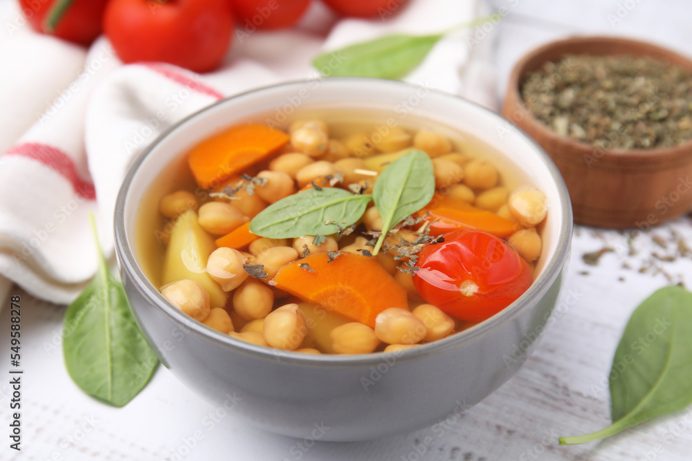 Tasty chickpea soup in bowl and spices on white wooden table, closeup Tasty chickpea soup in bowl and spices on white wooden table, closeup