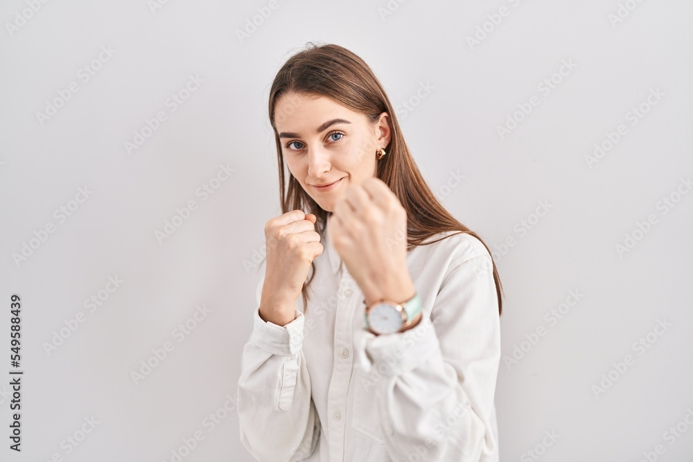 Young caucasian woman standing over isolated background ready to fight with fist defense gesture, angry and upset face, afraid of problem Young caucasian woman standing over isolated background ready to fight with fist defense gesture, angry and upset face, afraid of problem