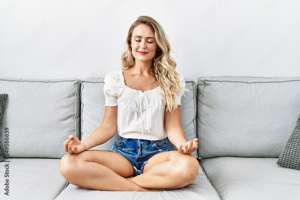 Young woman doing yoga exercise sitting on sofa at home Young woman doing yoga exercise sitting on sofa at home
