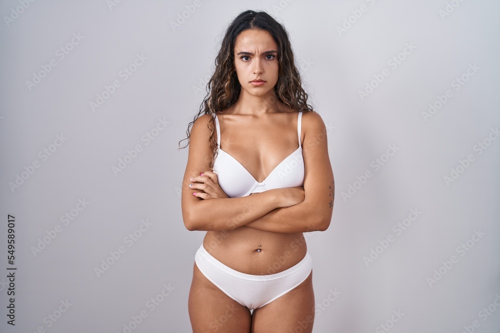 Fototapeta premium Young hispanic woman wearing white lingerie skeptic and nervous, disapproving expression on face with crossed arms. negative person.