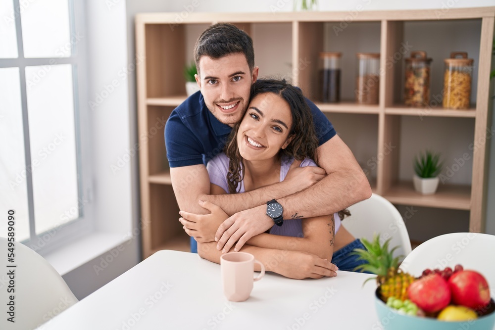Young hispanic couple drinking coffee sitting on table at home Young hispanic couple drinking coffee sitting on table at home