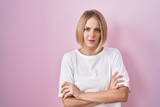 Young caucasian woman standing over pink background skeptic and nervous, disapproving expression on face with crossed arms. negative person.