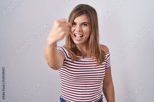 Wallpaper Mural Young hispanic woman standing over isolated background angry and mad raising fist frustrated and furious while shouting with anger. rage and aggressive concept. Torontodigital.ca