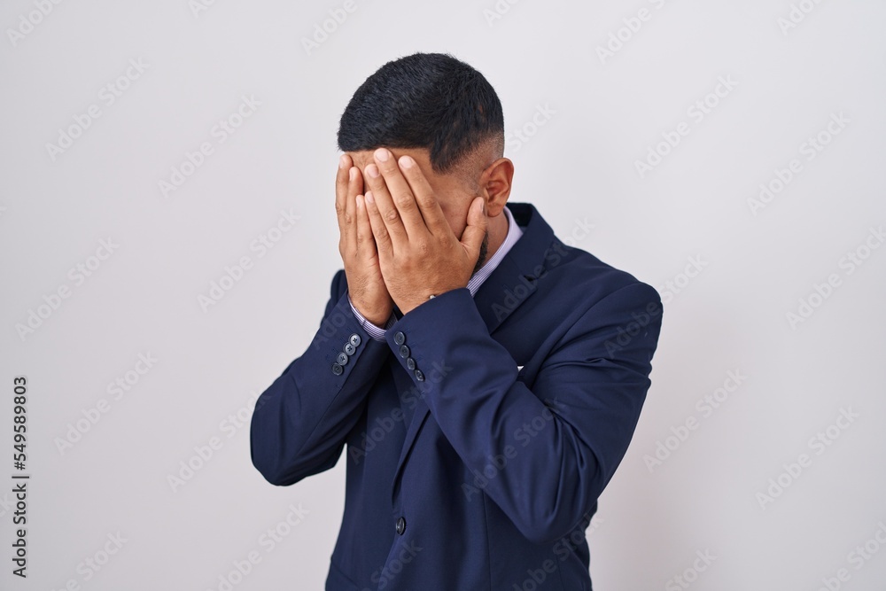 Young hispanic man wearing business suit and tie with sad expression covering face with hands while crying. depression concept. Young hispanic man wearing business suit and tie with sad expression covering face with hands while crying. depression concept.