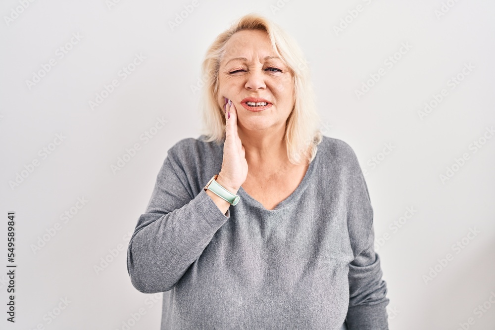 Middle age caucasian woman standing over white background touching mouth with hand with painful expression because of toothache or dental illness on teeth. dentist Middle age caucasian woman standing over white background touching mouth with hand with painful expression because of toothache or dental illness on teeth. dentist