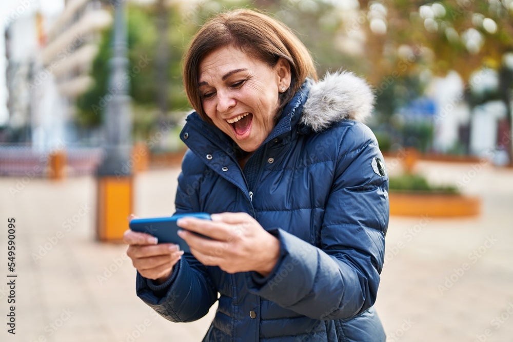 Fototapeta premium Middle age woman smiling confident watching video on smartphone at park
