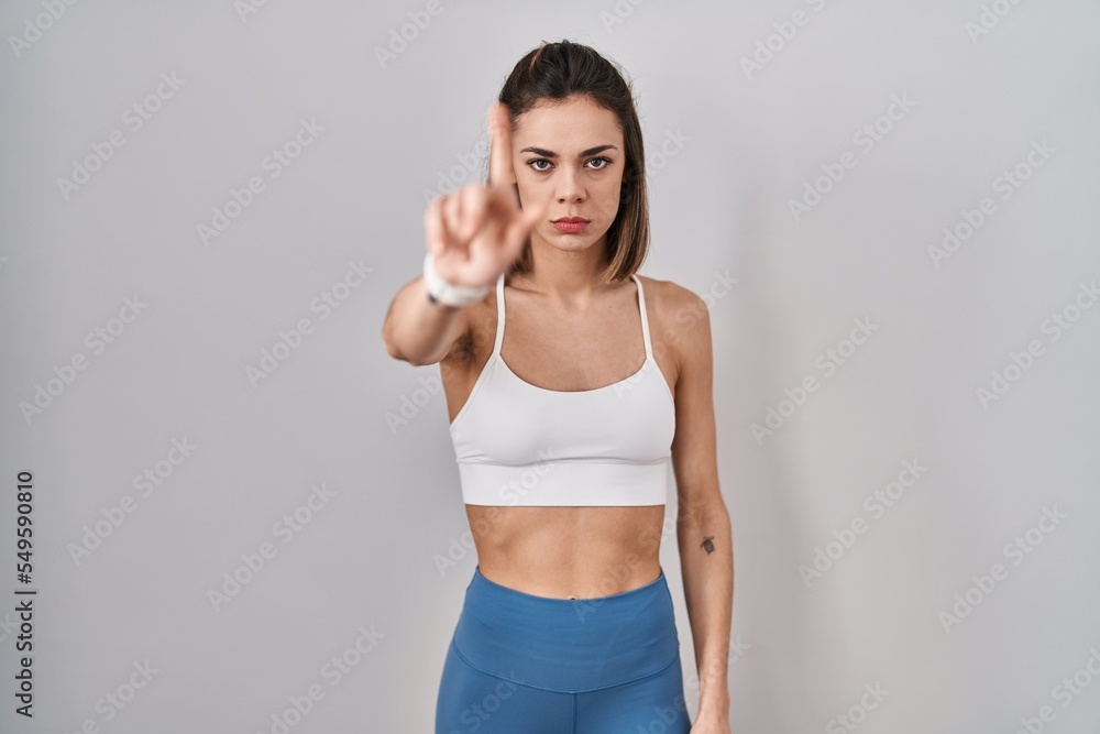 Hispanic woman wearing sportswear over isolated background pointing with finger up and angry expression, showing no gesture