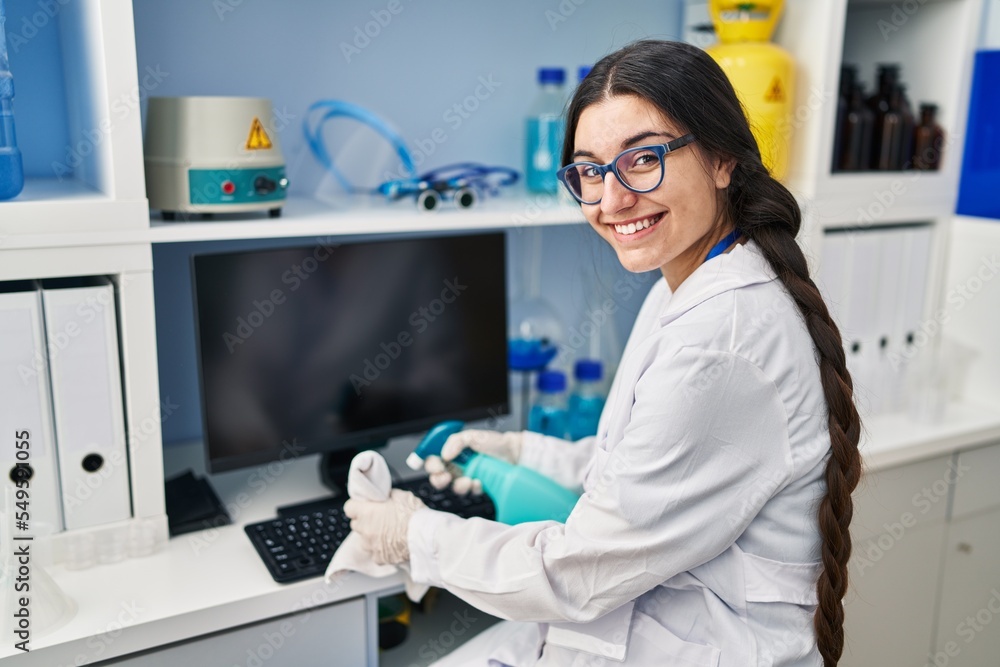 Young hispanic woman wearing scientist uniform cleaning using sanitizer gel at laboratory Young hispanic woman wearing scientist uniform cleaning using sanitizer gel at laboratory