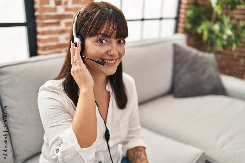 Young beautiful hispanic woman call center agent sitting on sofa working at home Young beautiful hispanic woman call center agent sitting on sofa working at home